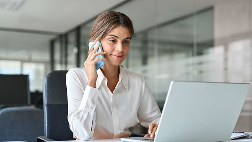 Frau telefoniert und schaut auf Laptop