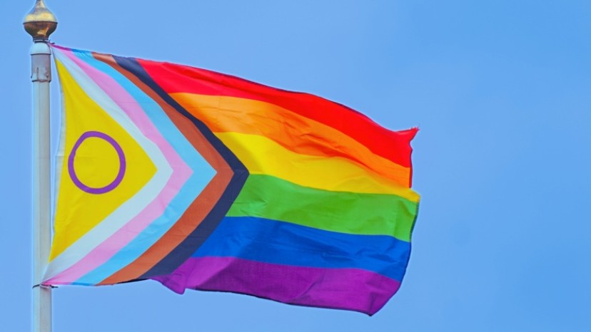 Eine Regenbogenflagge weht an einem Fahnenmast.