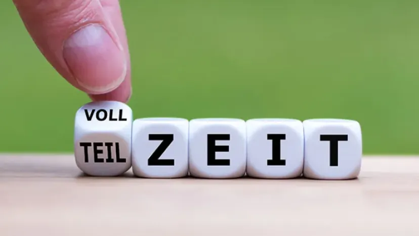 Hand dreht einen Würfel und ändert das Wort "Teilzeit" in "Vollzeit".