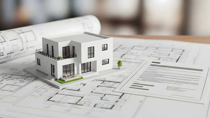 Architektur-Modell eines modernen Hauses mit Konstruktionsplänen auf einem Holztisch