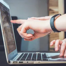 Finger zeigen auf aufgeklappten Laptop-Bildschirm