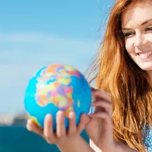 Frau hält Miniatur-Weltkugel in der Hand