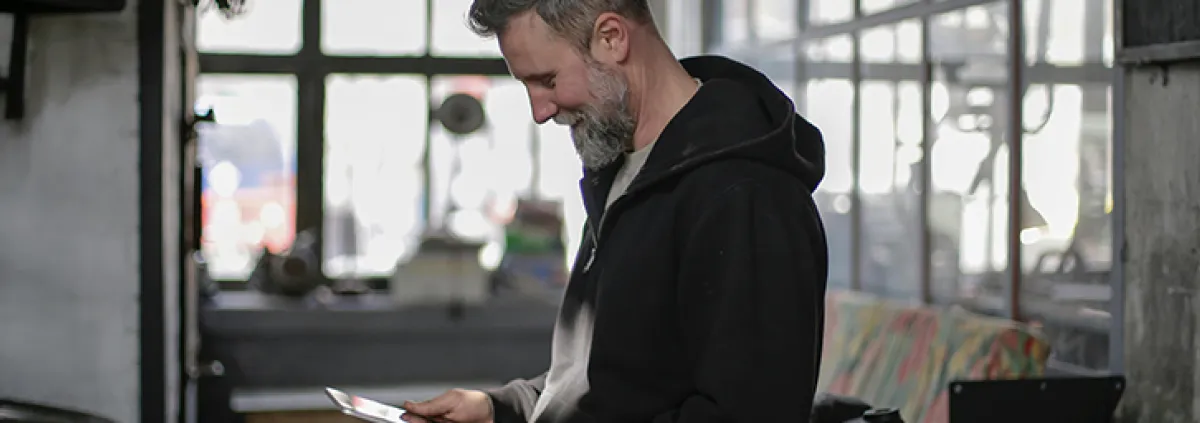 Mann blickt auf Tablet in seinen Händen