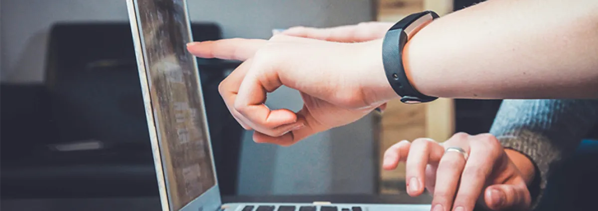 Finger zeigen auf aufgeklappten Laptop-Bildschirm