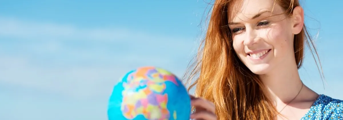 Frau hält Miniatur-Weltkugel in der Hand